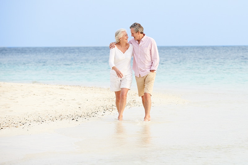 Romantic Senior Couple Walking On Beautiful Tropical Beach